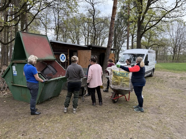 Helfer entsorgen gesammelten Schrott und Müll in einem Container auf dem Vereinsgelände.