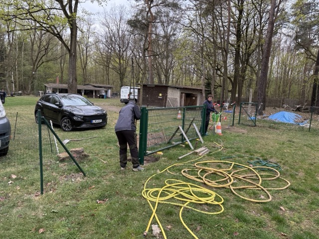 Helfer montieren ein Zaunelement und arbeiten am neuen Tor auf dem Vereinsgelände.